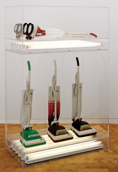 Jeff Koons, New Hoover Convertibles, Green, Red, Brown, New Hoover Deluxe Shampoo Polishers, Yellow, Brown Doubledecker, 1981-87, three vacuum cleaners, two shampoo polishers, and fluorescent lights in Plexiglas casing, overall 82 5/8 by 54 by 28 inches. Courtesy: Glenstone. Photo: Tim Nighswander © Jeff Koons